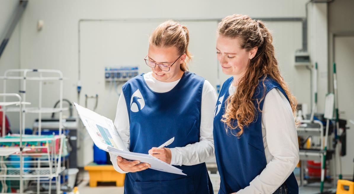 Taal werkt! Twee medewerkers schoonmaak vullen formulier in