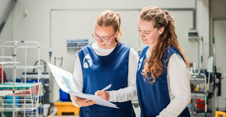 Taal werkt! Twee medewerkers schoonmaak vullen formulier in